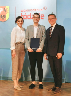 trzy osoby stoją obok siebie, po środku laureat nagrody